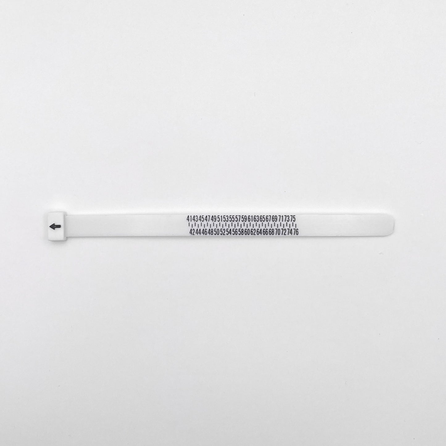 Image d'un baguier de la boutique Altiplano, spécialisé dans les bijoux en argent latino-américains. Cet outil en plastique blanc est utilisé pour mesurer la taille des bagues, avec des graduations numérotées pour une lecture précise.