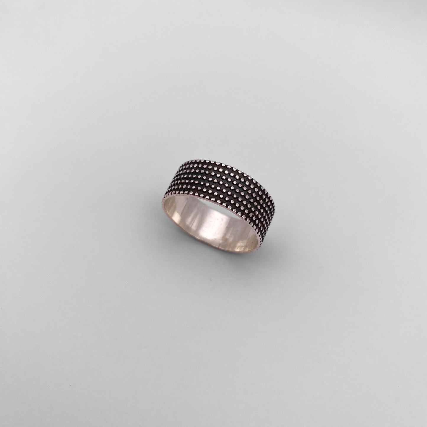 Bague en argent "JAYRI" de la boutique Altiplano, présentant un motif de pois texturés distinctifs sur fond noir. Bijou artisanal latino-américain, élégant et unique.