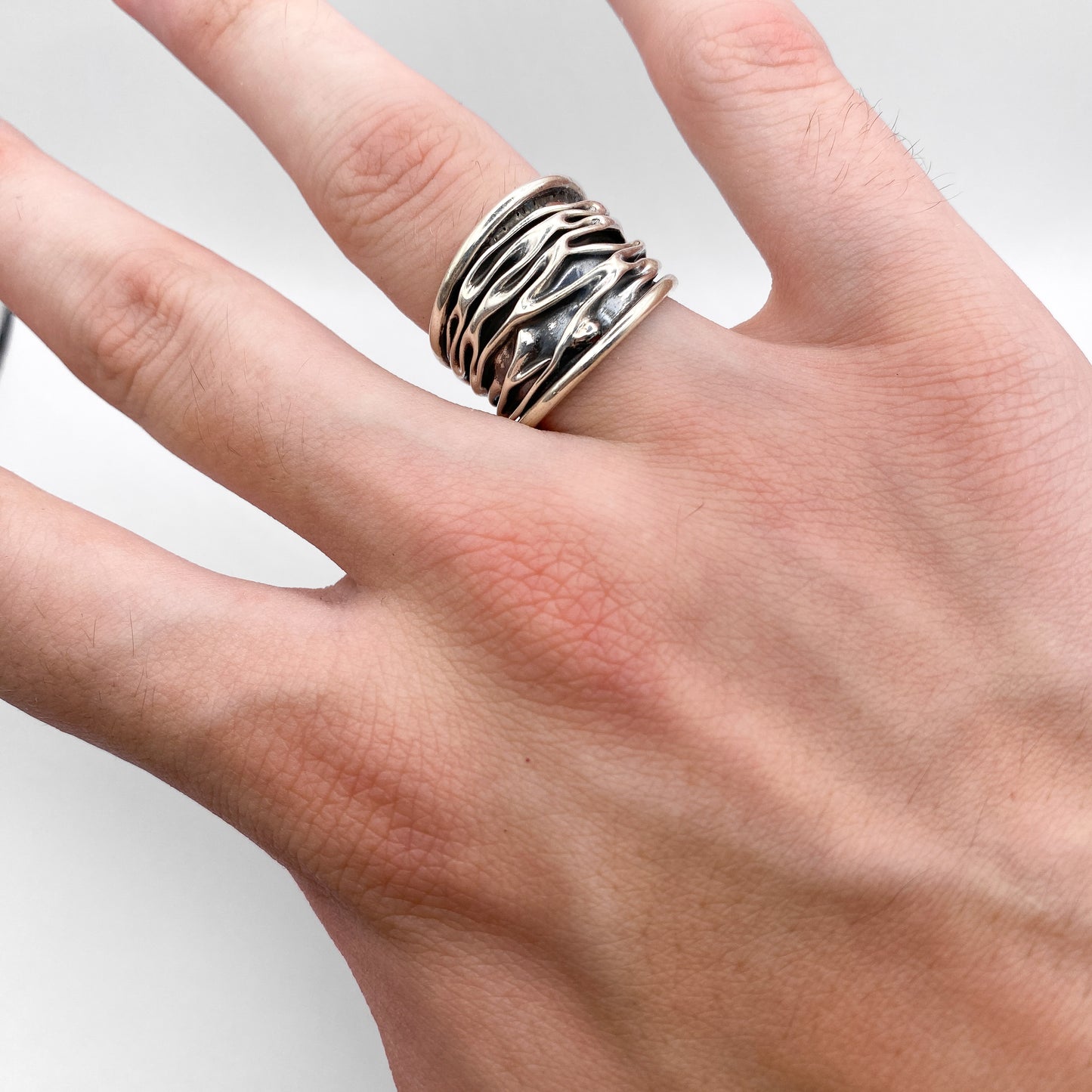 Bague en argent de la collection "WAYRA" par Altiplano, présentant un design ondulé et distinctif, portée sur la main d'une personne.