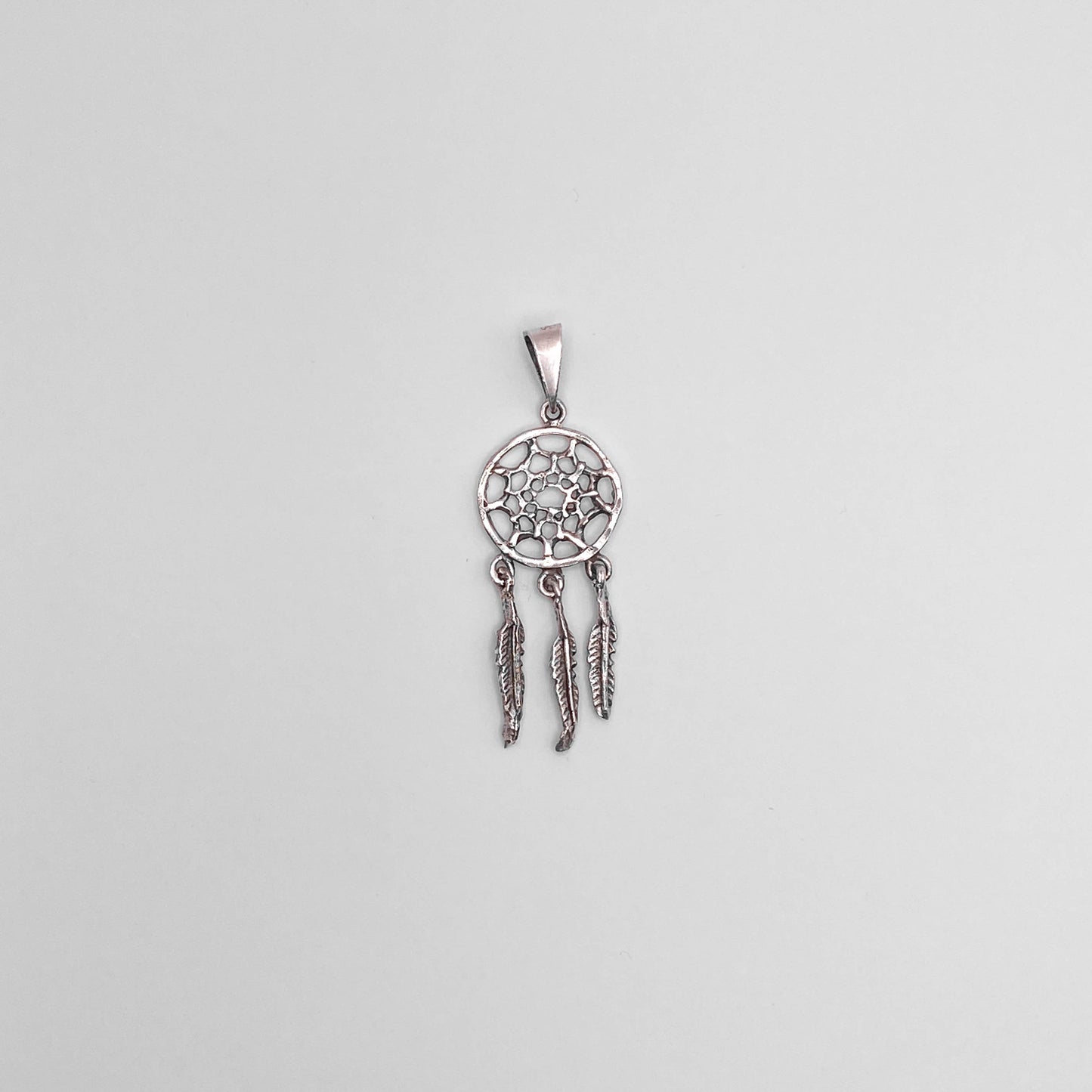 Pendentif en argent finement ciselé représentant un attrape-rêves avec trois plumes pendantes. Parfait pour ajouter une touche bohème à votre look. Disponible dans la boutique en ligne Altiplano, spécialisée dans les bijoux en argent latino-américains.