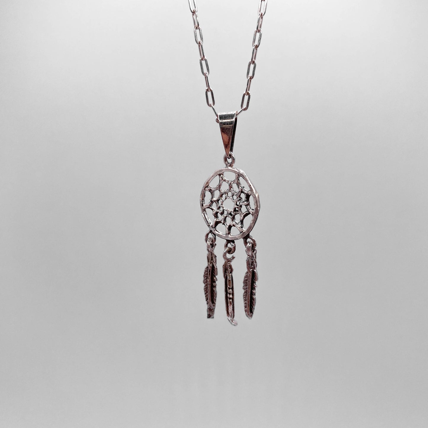 Pendentif en argent "OJIBWÉ" de la boutique Altiplano, inspiré par les attrapes-rêves traditionnels avec trois petites plumes pendantes.