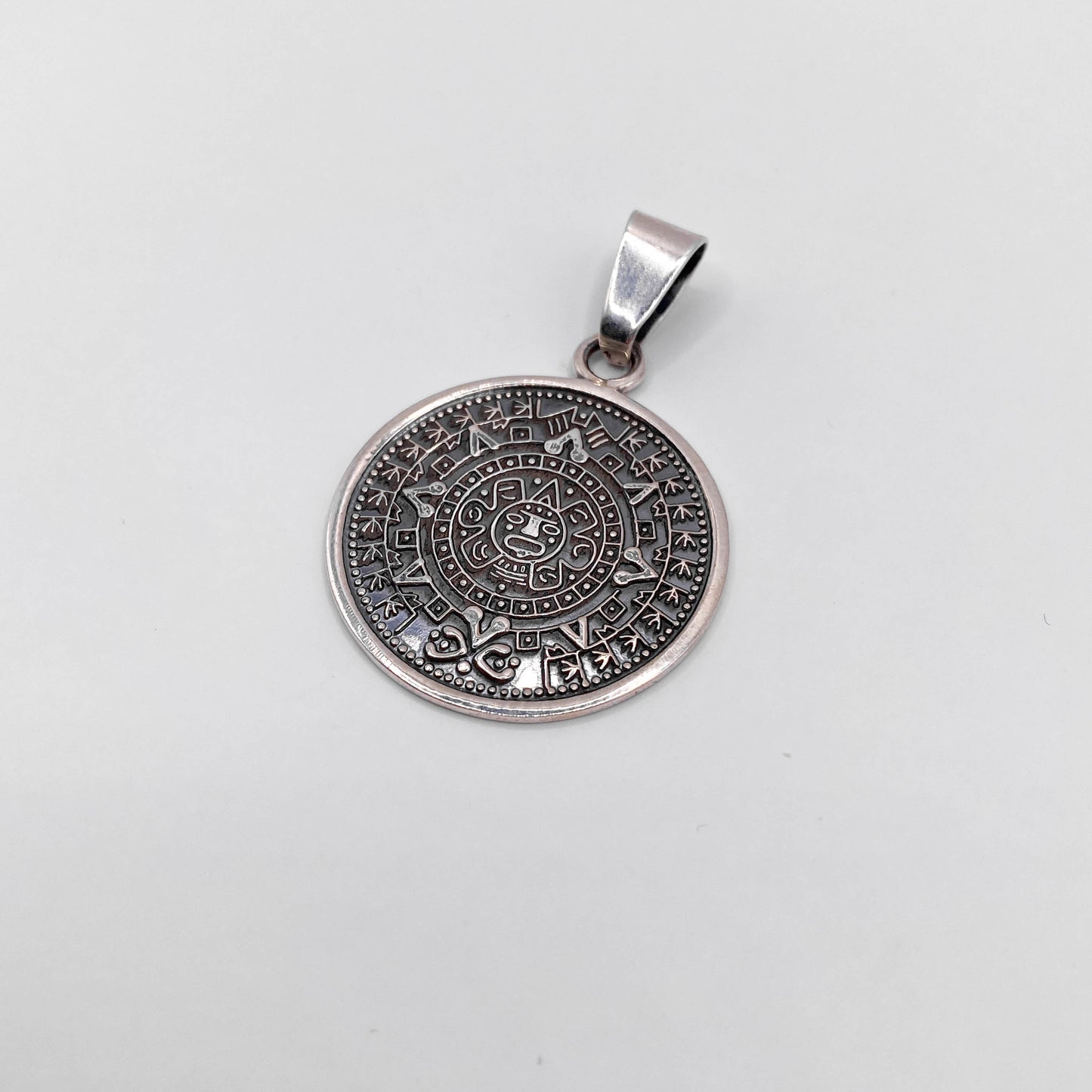 Pendentif rond en argent "AZTECA" de la boutique Altiplano, orné de motifs aztèques détaillés, évoquant l'artisanat latin américain traditionnel.