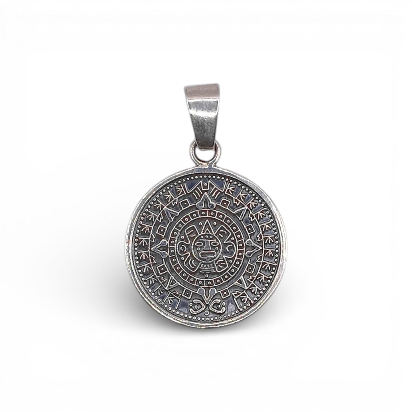 Un pendentif rond en argent finement ciselé, représentant un motif aztèque détaillé, disponible sur la boutique en ligne de bijoux Altiplano.