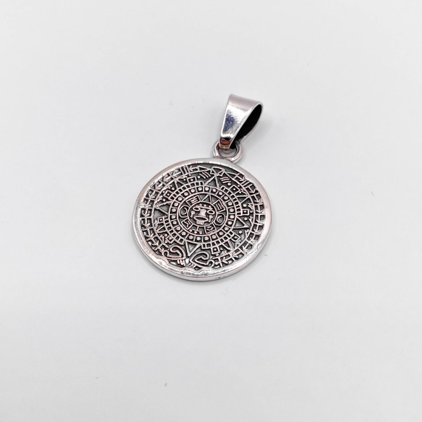 Pendentif en argent "OMEKA'" de la boutique Altiplano, représentant un motif circulaire détaillé inspiré de l'art latino-américain.