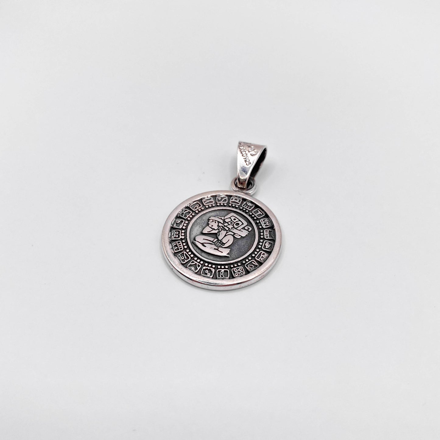 Pendentif en argent de la boutique Altiplano, représentant une figure symbolique latino-américaine entourée de motifs traditionnels.