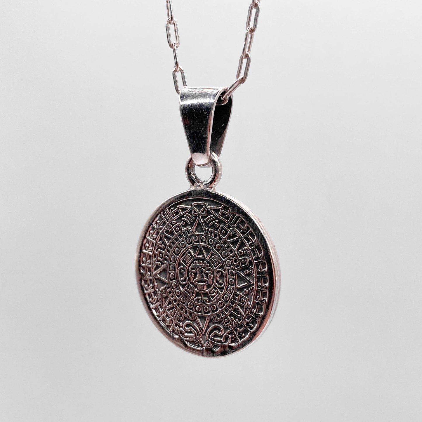 Colier en argent de la boutique Altiplano, intitulé "OMEKA'", présentant un pendentif rond finement gravé d'un motif inspiré de l'art latino-américain.
