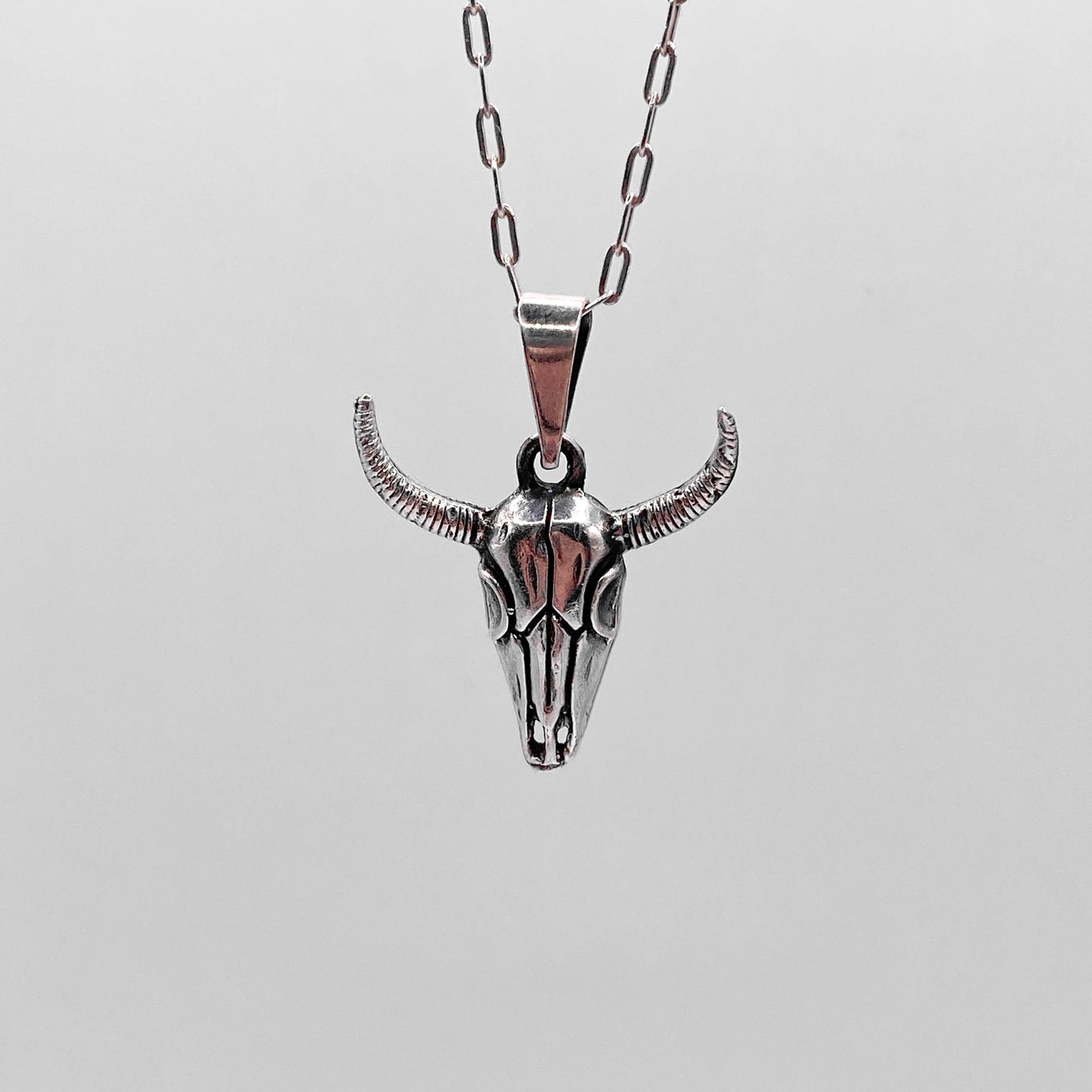 Collier en argent de la boutique Altiplano intitulé "MICTLAN", représentant un pendentif en forme de crâne de taureau avec des détails fins et des cornes incurvées.