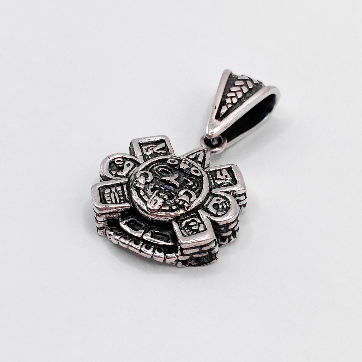 Pendentif en argent "OLLIN" de la boutique Altiplano, inspiré de motifs traditionnels latino-américains, conçu avec des détails complexes et un charme authentique.