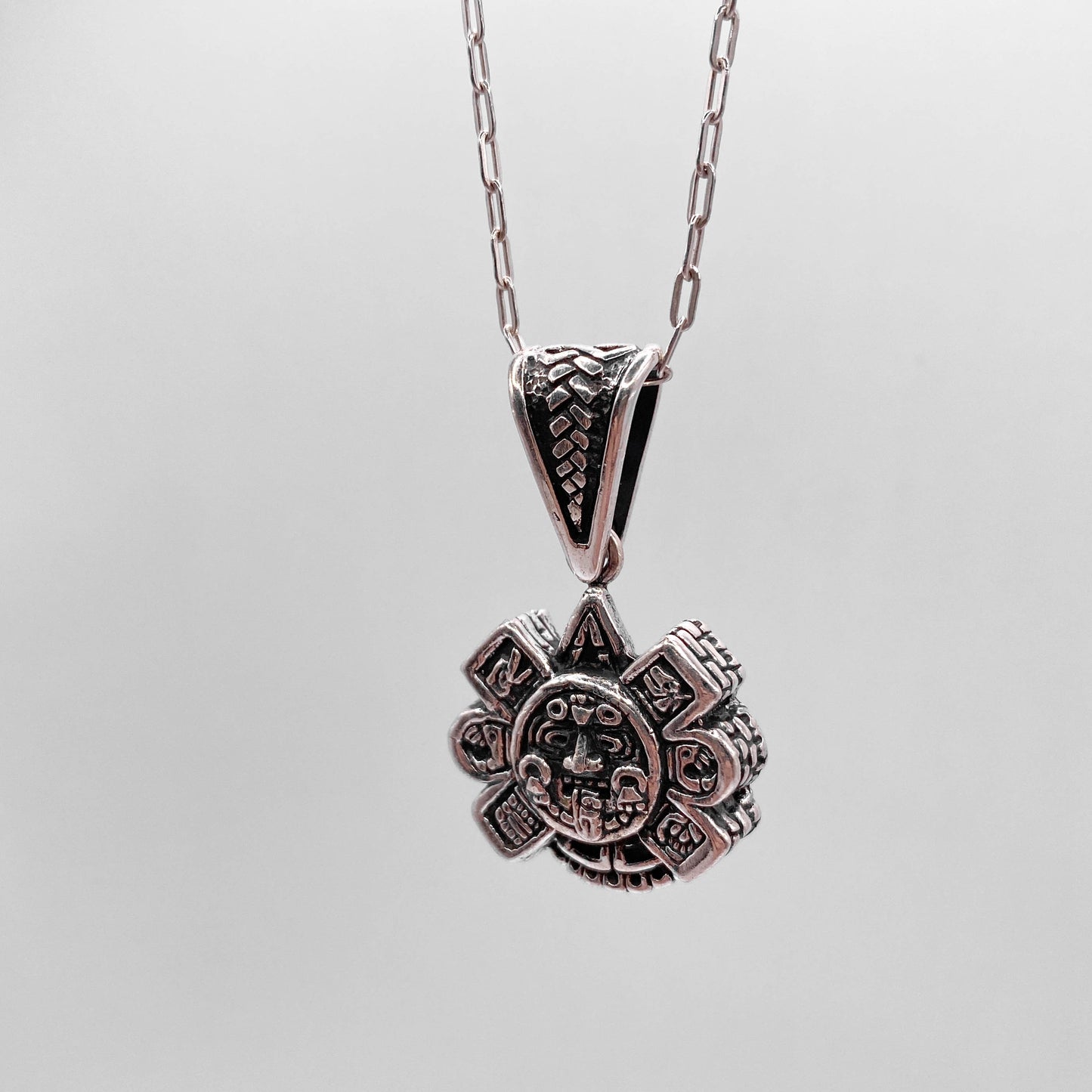 Collier en argent "OLLIN" de la boutique Altiplano, avec un pendentif décoré d'un motif artistique riche en détails inspiré par l'art latino-américain.
