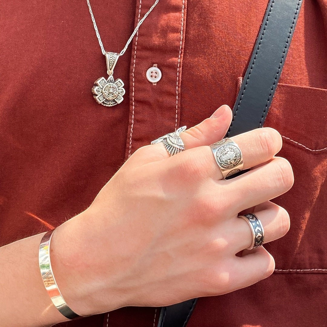 Modèle portant des bijoux en argent de la collection 'Chacana' de la boutique Altiplano, incluant une chaîne avec un pendentif orné, plusieurs bagues et un bracelet.