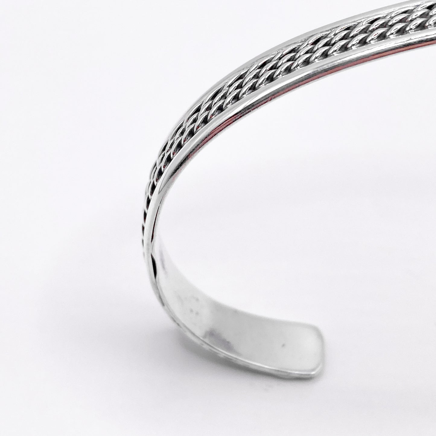 Bracelet en argent "AWANA" de la boutique Altiplano, présenté avec un motif tressé élégant et un design ouvert, reflétant l'artisanat latino-américain.