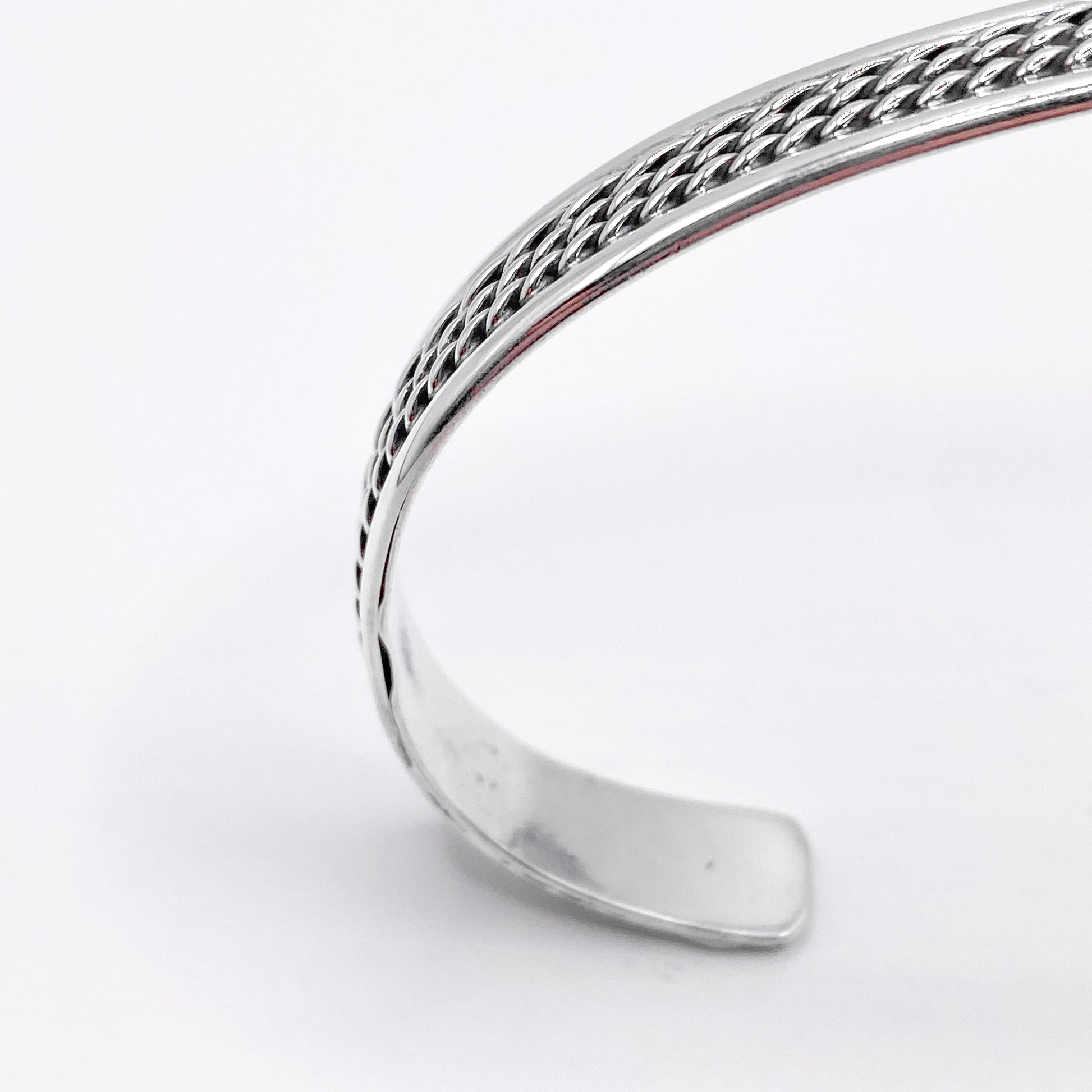 Bracelet en argent "AWANA" de la boutique Altiplano, présenté avec un motif tressé élégant et un design ouvert, reflétant l'artisanat latino-américain.