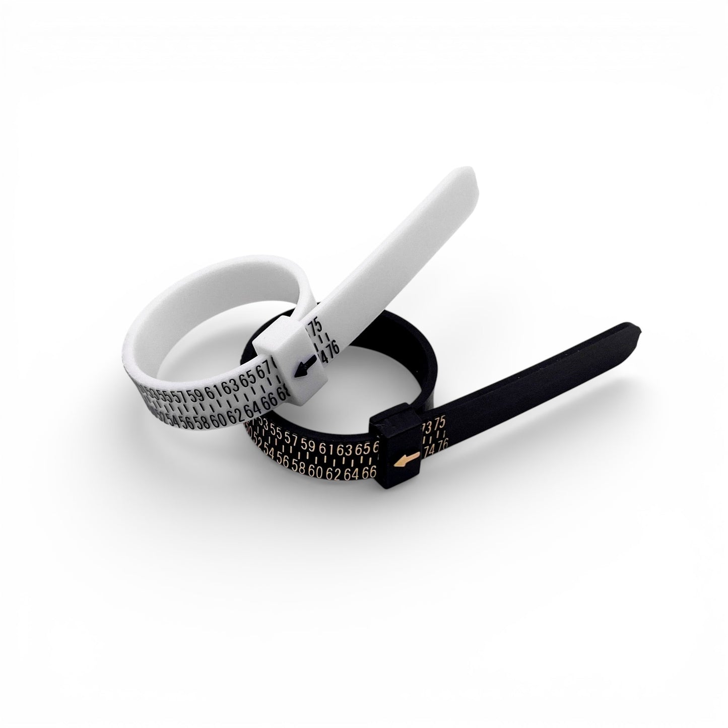 Photo de deux baguiers (Anneaux de mesure pour les tailles de bague) de couleur noire et blanche posés côte à côte sur un fond blanc. Les baguiers affichent des graduations de taille en chiffres dorés et noirs, avec une petite flèche indiquant la taille. Produit par la boutique de bijoux en argent "Altiplano".