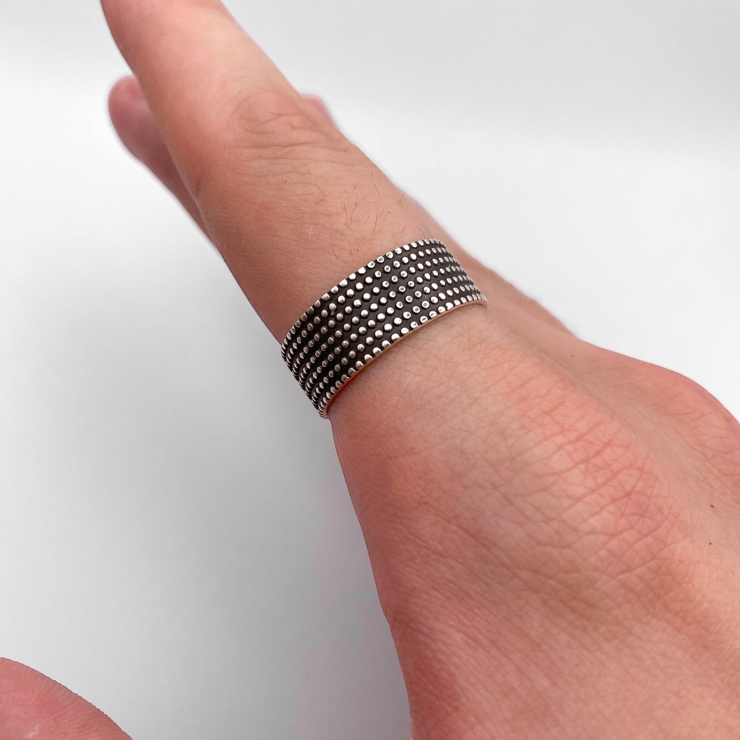 Bague en argent JAYRI ornée de motifs perlés délicats, disponible sur la boutique en ligne Altiplano, spécialisée dans les bijoux latino-américains. Photographie d'un doigt portant la bague sur un fond blanc.