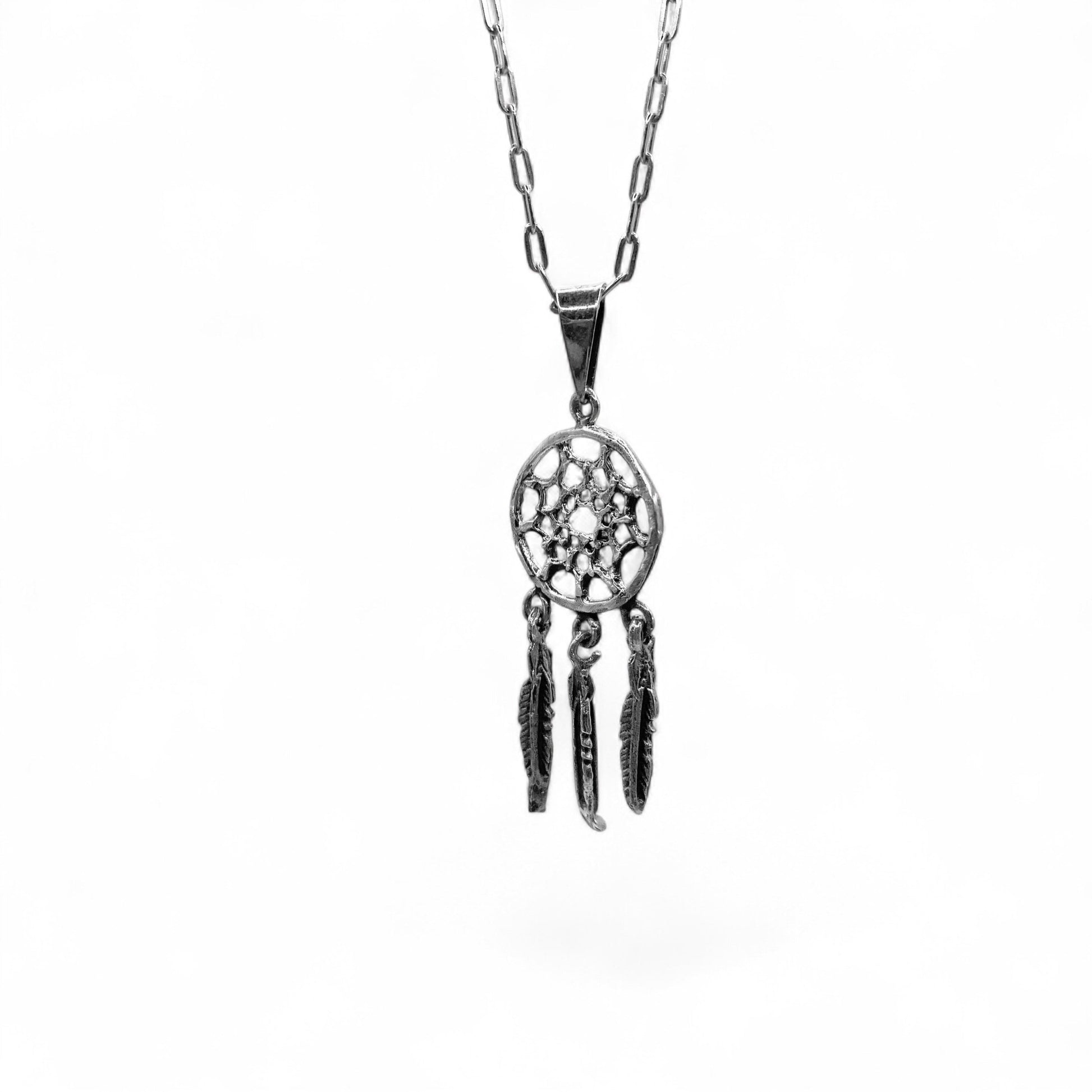 Pendentif en argent "OJIBWÉ" de la boutique Altiplano, inspiré par les attrapes-rêves traditionnels avec trois petites plumes pendantes.