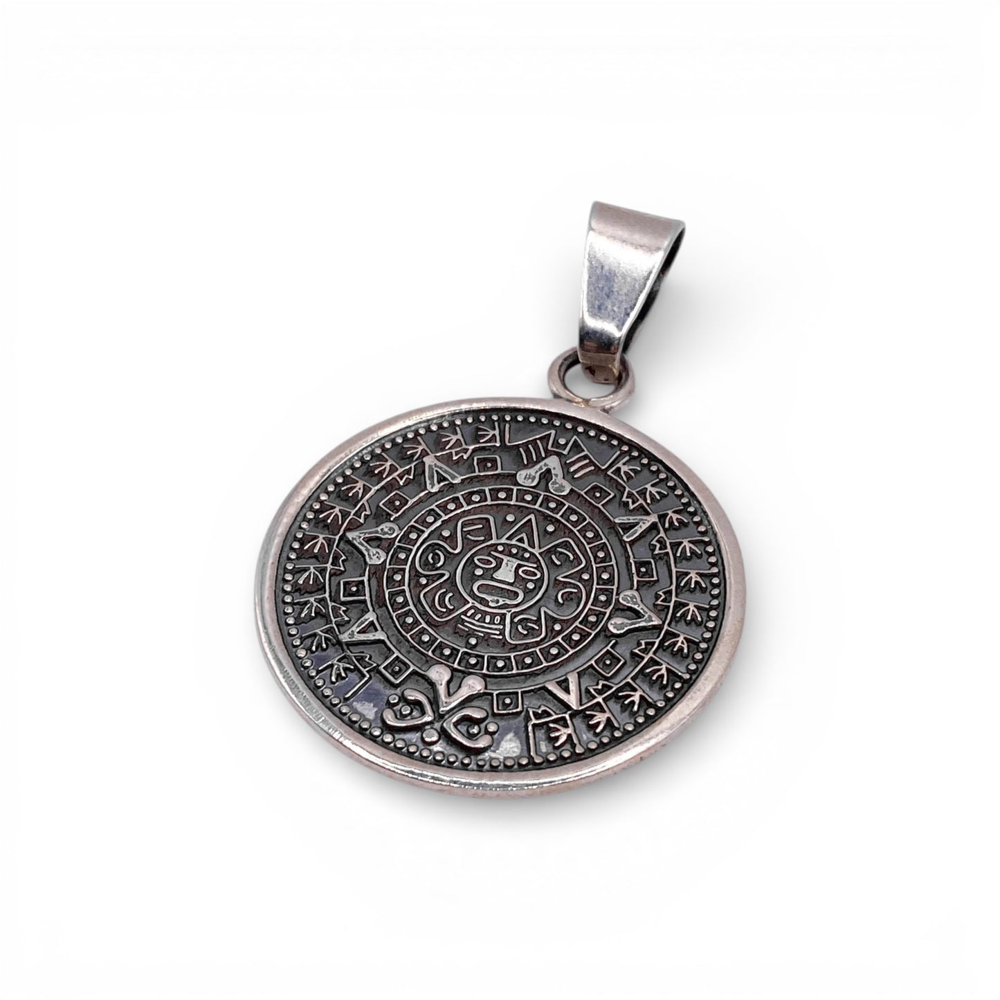 Pendentif rond en argent finement gravé représentant un calendrier aztèque, disponible dans la boutique Altiplano.