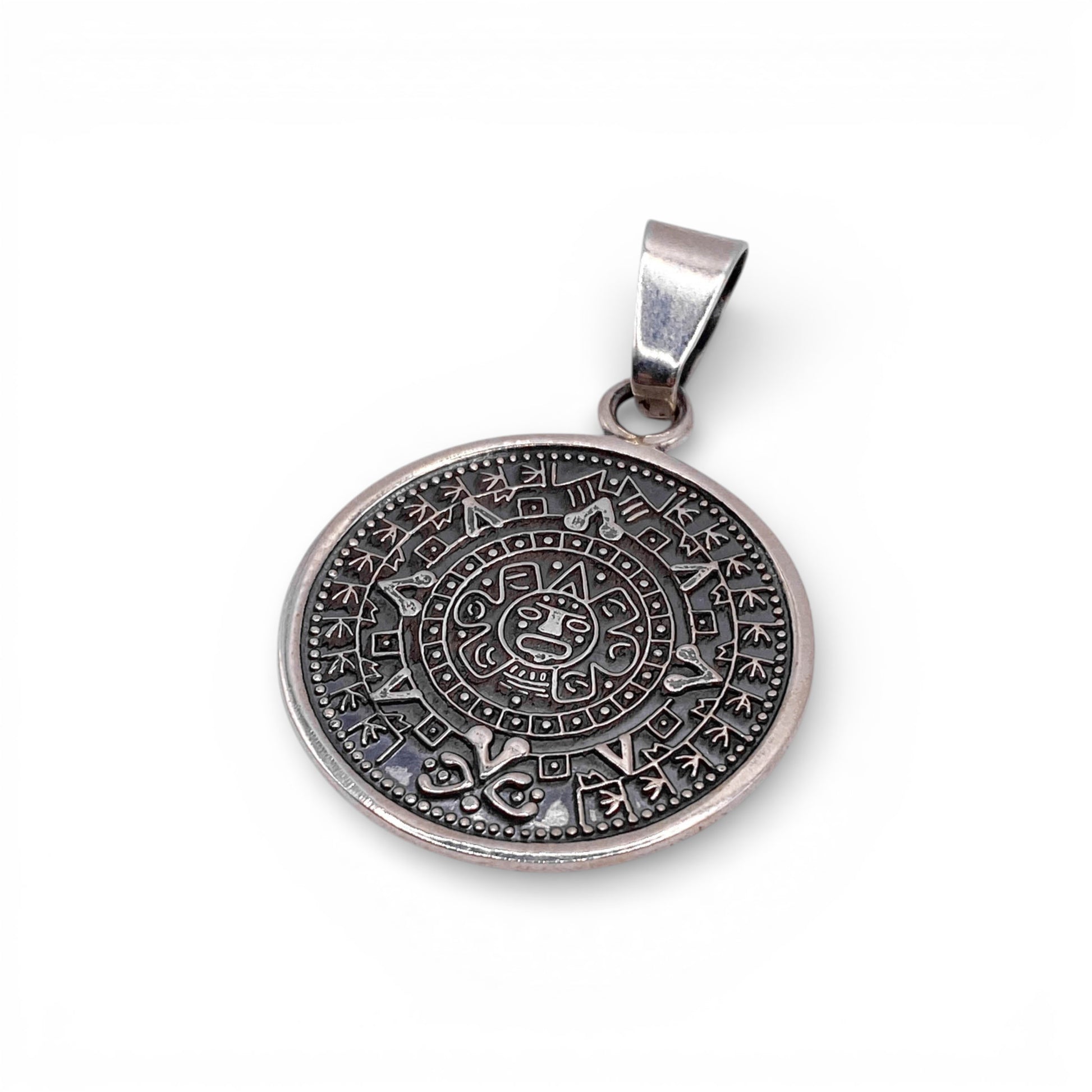 Pendentif rond en argent finement gravé représentant un calendrier aztèque, disponible dans la boutique Altiplano.