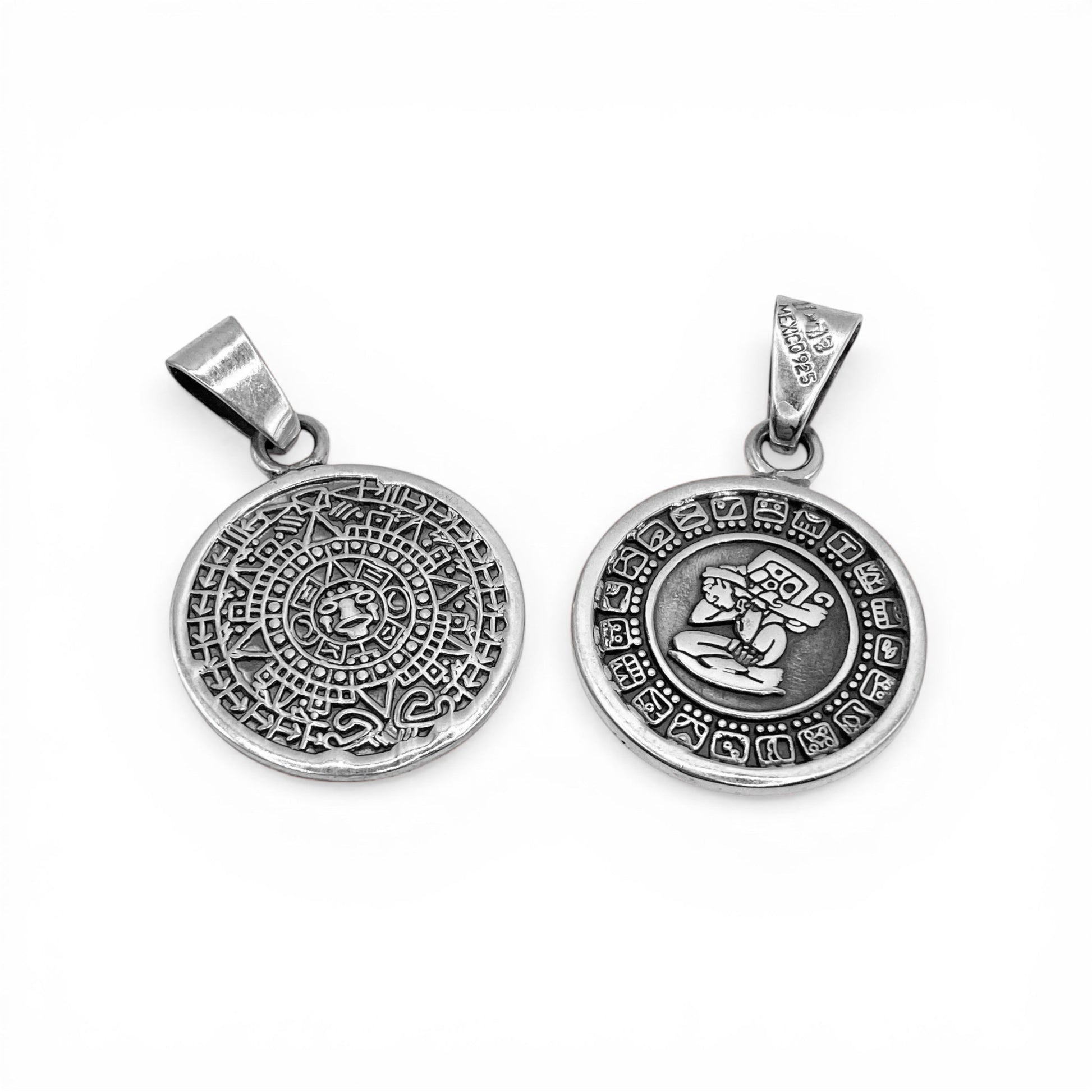 Deux pendentifs en argent à motifs aztèques disponibles sur la boutique en ligne Altiplano. Le premier pendentif présente un calendrier maya, tandis que le second met en avant un personnage gravé entouré de symboles mayas.