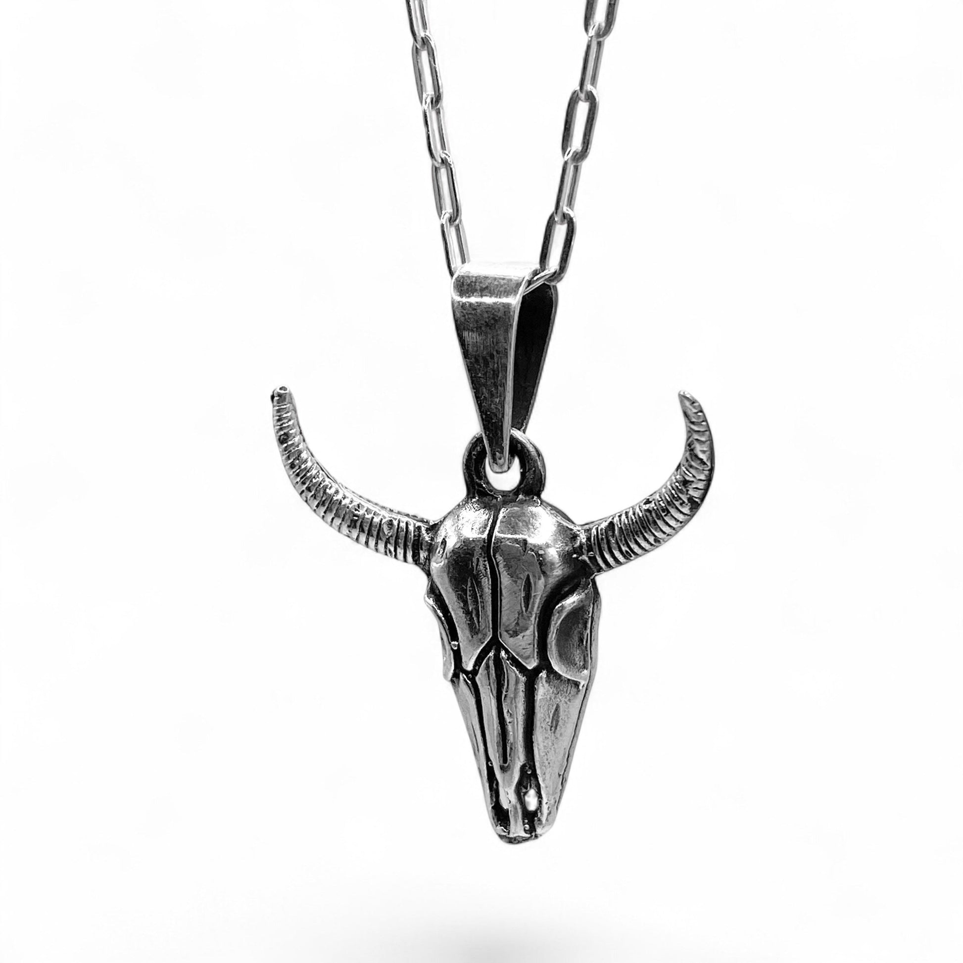 Un collier en argent avec un pendentif en forme de tête de bison ornée de cornes, proposé par la boutique de bijoux latino-américains "Altiplano". Le design détaillé et le métal poli confèrent une allure unique et artisanale à ce bijou intitulé "MICTLAN".
